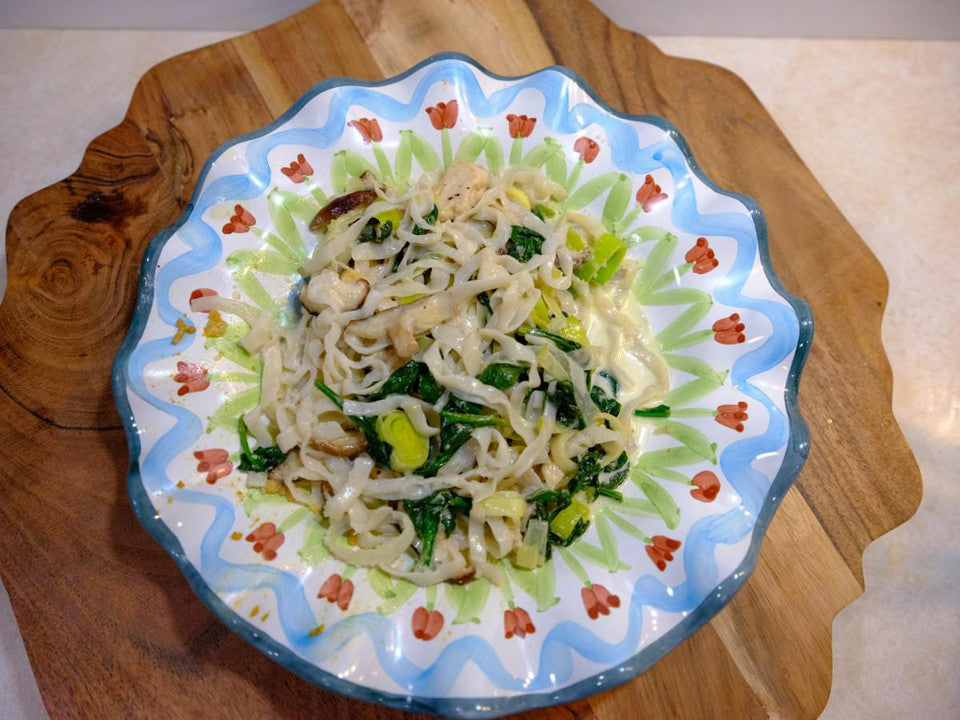A festive plate sat on a wooden block filled with keto-friendly, low-carb chicken fettuccine.