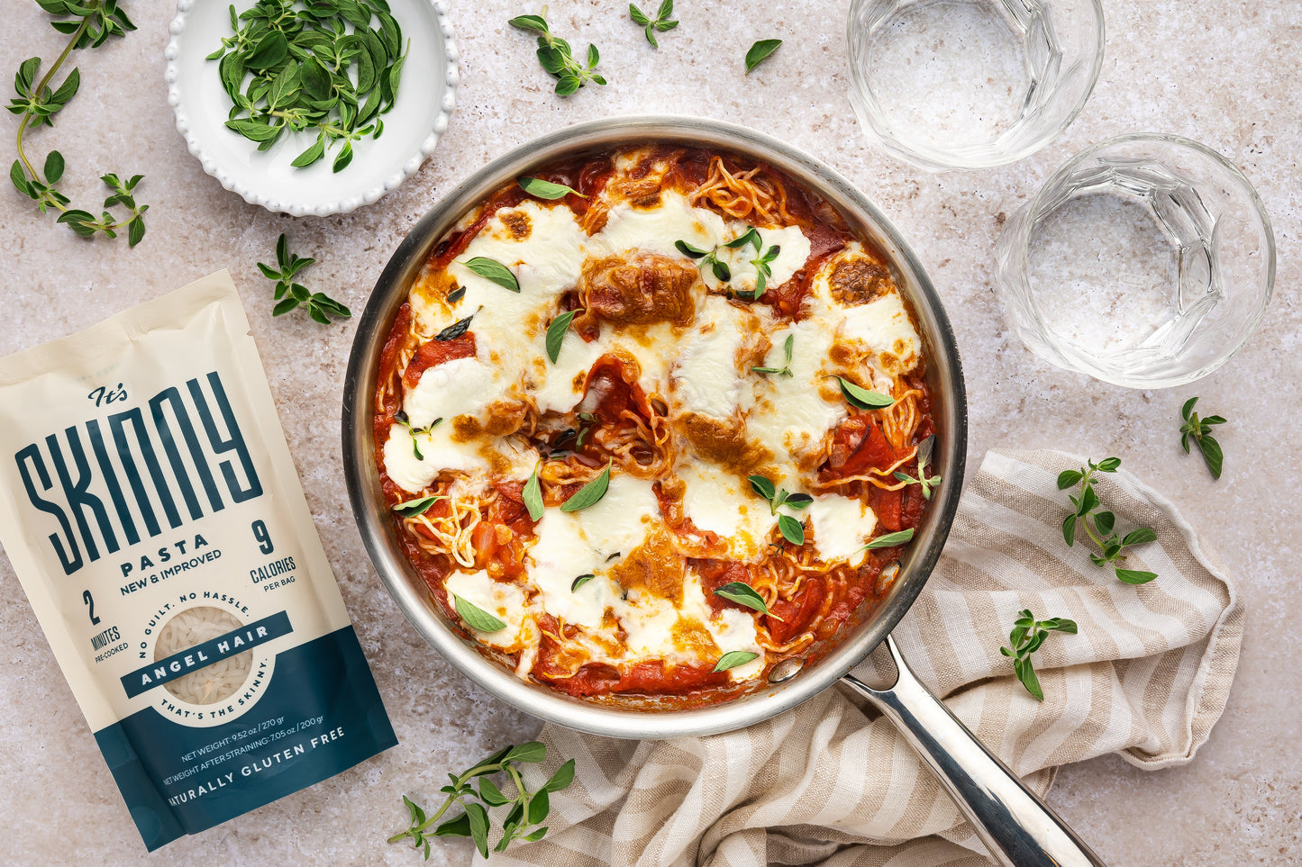An overhead image of a skillet of low-carb pepperoni pizza pasta, topped with melty cheese and fresh basil.