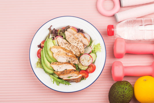 Fitness and active healthy lifestyles presentation concept with a plate of chicken breast salad, a lime, lemon, weights, and a bottle of water.
