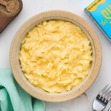 An overhead image of a bowl of low carb It's Skinny Mac and Cheese served on a white tabletop.