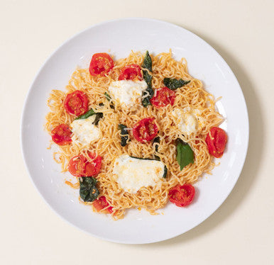 An overhead image of a cheesy tomato pasta made with It's Skinny Angel Hair, mozzarella cheese, and tomatoes.