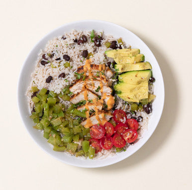 An overhead image of a low-carb rice bowl made with It's Skinny Rice and beans, peppers, avocado, tomatoes, and sliced chicken.